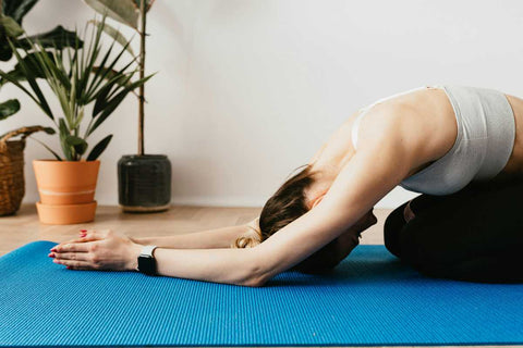 1. Ce exercitii poti face pentru drenajul limfatic_Miscari simple pentru reducerea retentiei de apa si revitalizarea organismului_Femeie facand exercitii de stretching sau yoga pe saltea, camera, plante